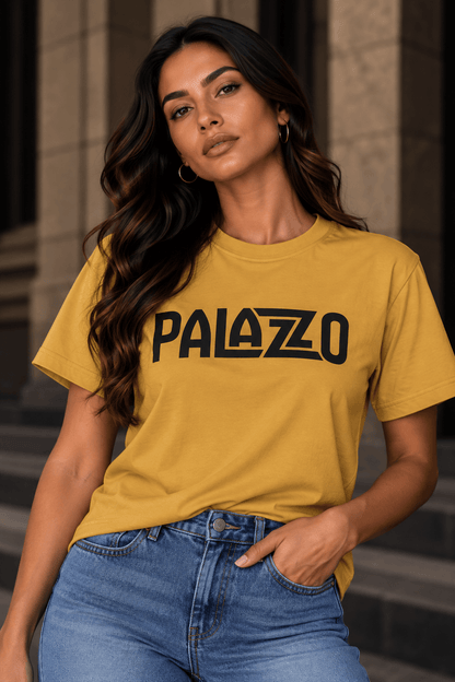 Frau in Sand 'PALAZZO' T-Shirt und Jeans, steht vor Treppen im Stadtzentrum, lässiger Streetwear-Style, urbanes Ambiente