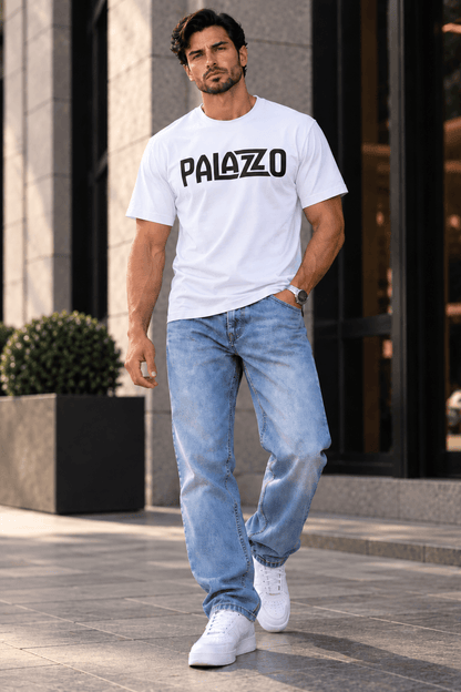 Mann trägt ein weißes T-Shirt mit schwarzem Palazzo-Logo, lässig in urbaner Umgebung, kombiniert mit blauen Jeans und weißen Sneakers