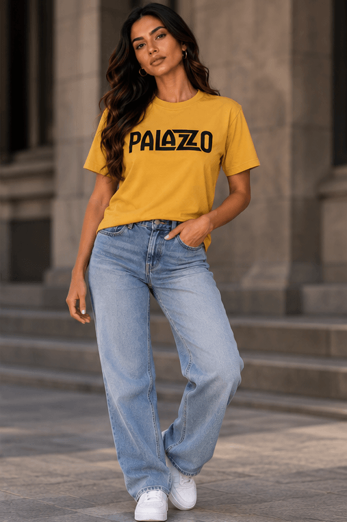 Männlicher Model mit dunklem Haar, trägt Sand 'PALAZZO' T-Shirt, schwarze Hosen, urbaner Hintergrund, modischer Streetwear-Look
