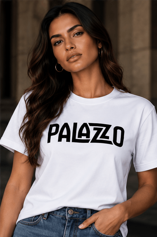 Nahaufnahme eines weiblichen Models in weißem T-Shirt mit 'PALAZZO'-Schrift, lässige Jeans, urbaner Hintergrund, modischer Streetwear-Look